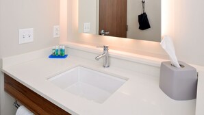 Une salle de bain avec un lavabo blanc, un miroir et un porte-serviettes.