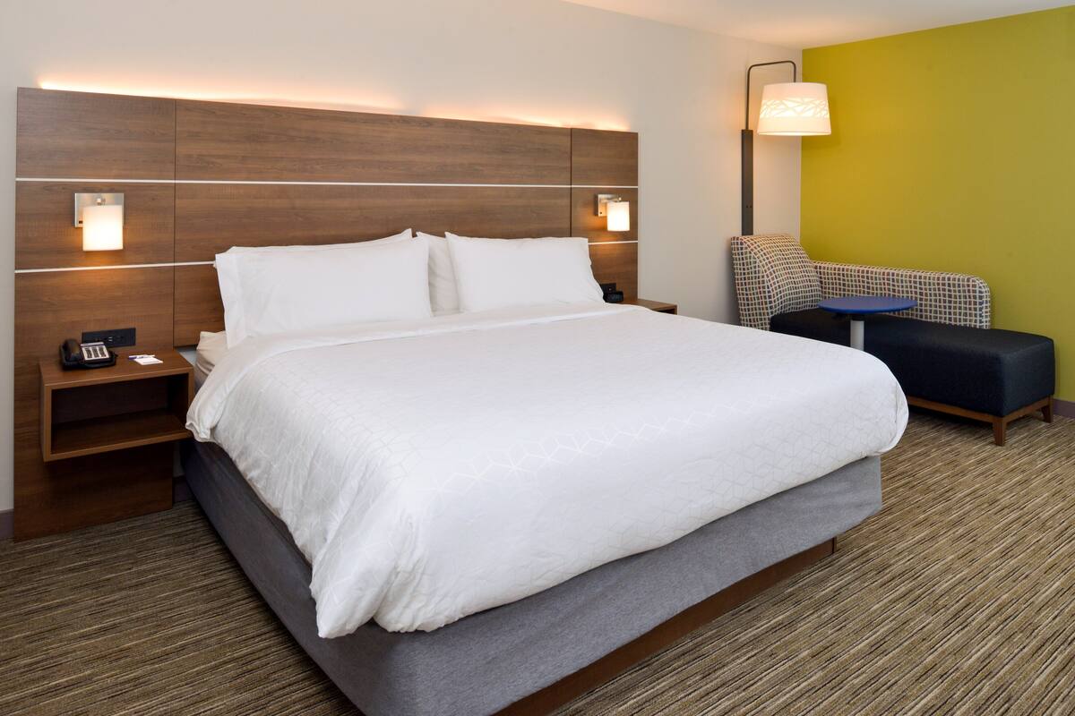 Ein Hotelzimmer mit einem großen Bett, Nachttischen, einem Sessel und einer Lampe.
