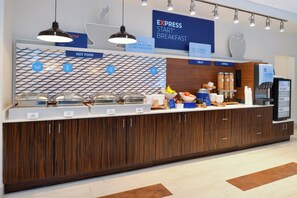 Zona de buffet con estaciones de comida señalizadas, que incluyen opciones calientes, fruta, cereales y yogur.