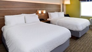 Une chambre d’hôtel avec deux lits, une table de chevet, une lampe et une fenêtre.