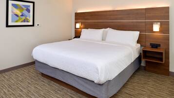 A hotel room with a large bed, a headboard with built-in lighting, a bedside table, and a wall-mounted artwork.