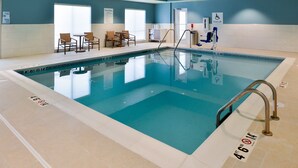 Une piscine équipée d’un dispositif d’élévation pour faciliter l’accès, de chaises longues et d’un panneau indiquant les règles d’utilisation de la piscine.