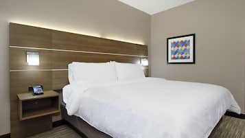 A hotel room with a large bed, a bedside table with a phone, and a wall-mounted light.