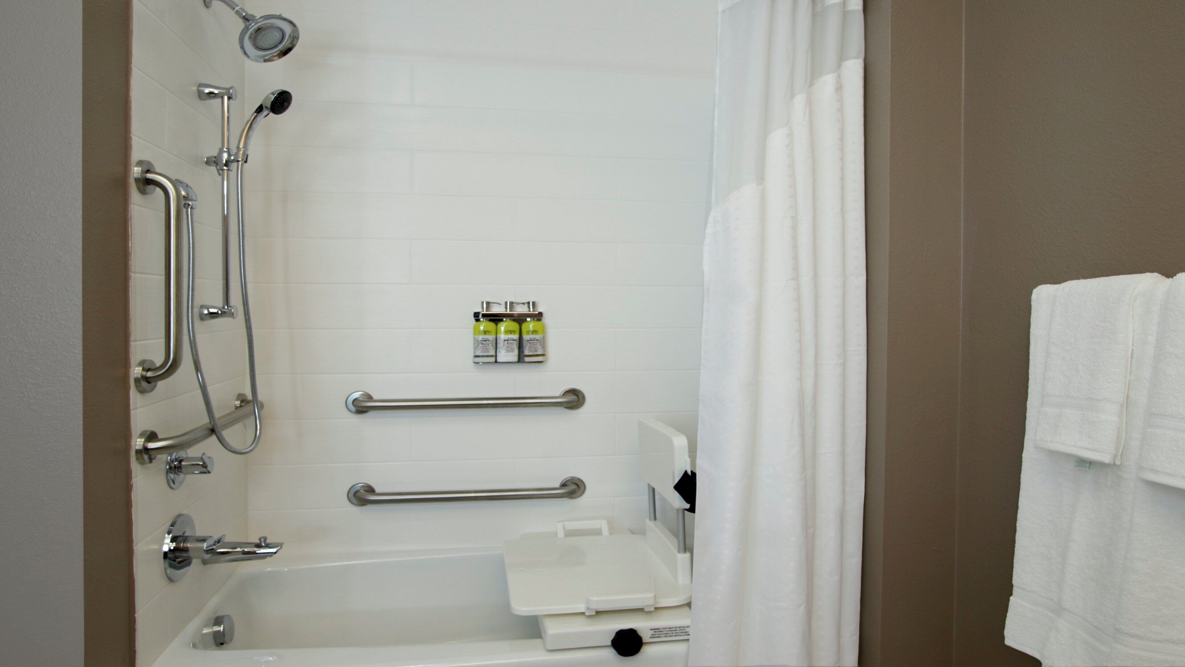 A bathroom with a bathtub, a shower, grab bars, and a towel rack.