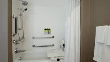 A bathroom with a bathtub, a shower, grab bars, and a towel rack.