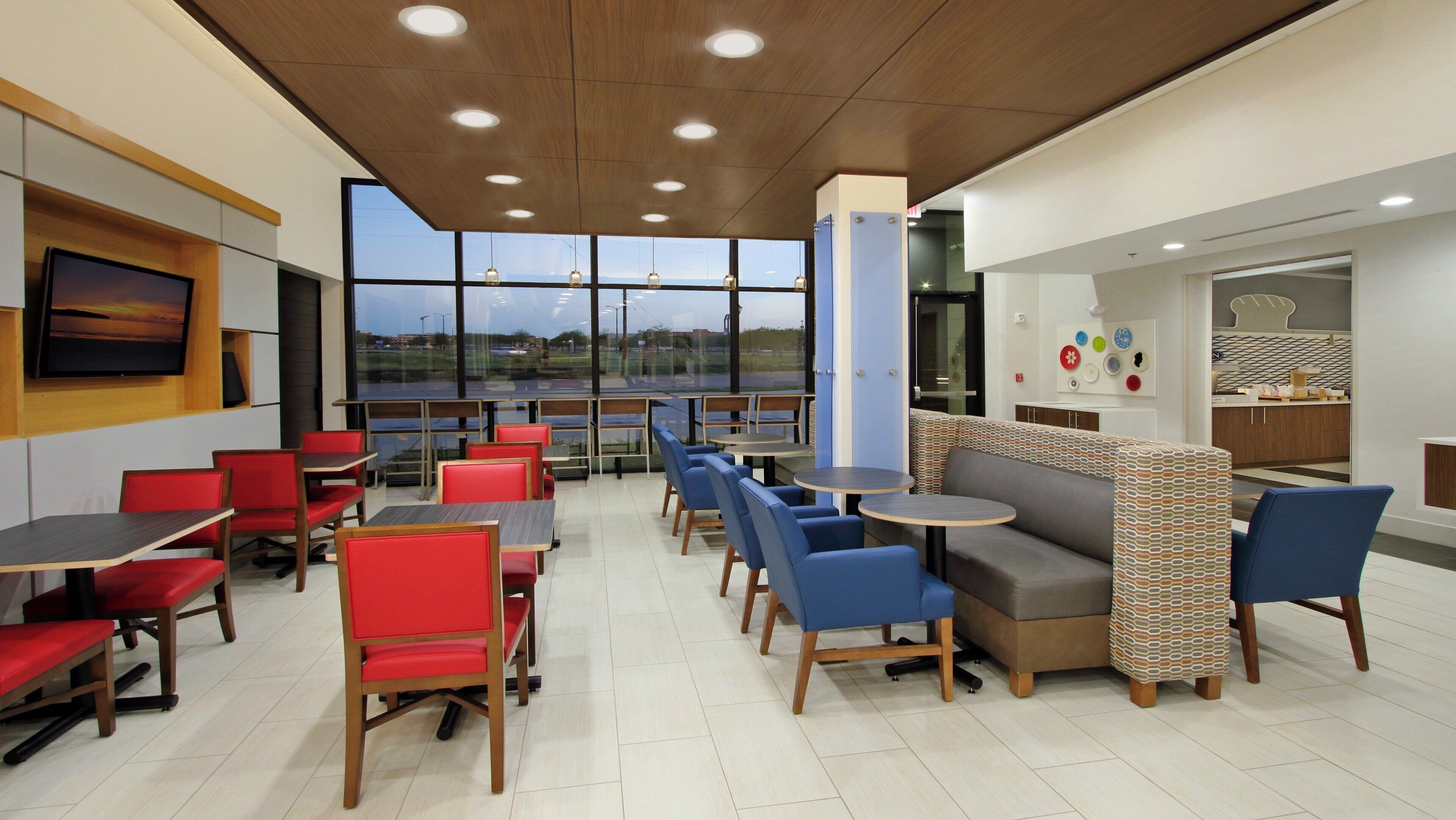A modern dining area with tables and chairs, a television, and a view of the outdoors.