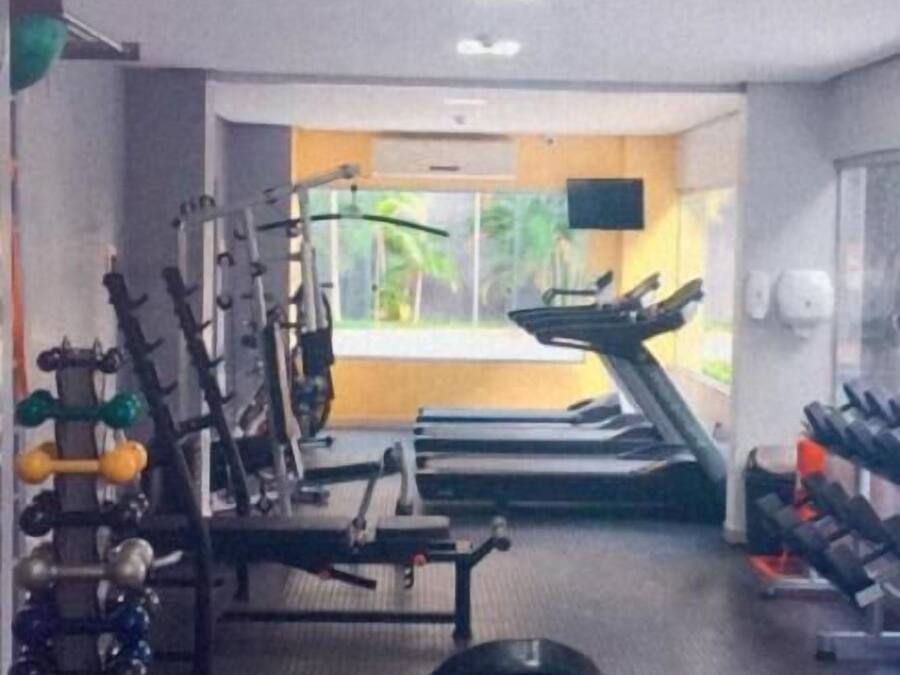 Un gimnasio con diverso equipo de ejercicio, incluyendo mancuernas, cinta de correr y máquinas de pesas.