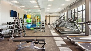 Un gimnasio con cintas de correr, mancuernas y pelotas de ejercicio.