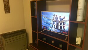 Uma sala de estar com uma TV de tela plana instalada em um móvel de madeira.
