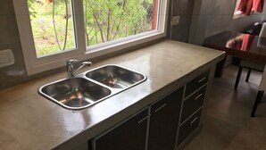 Uma cozinha com uma pia de aço inoxidável, uma janela com vista para o verde e um balcão.