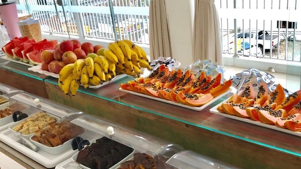 A buffet with various food items including fruits, bread, and desserts. - Hotel Pousada Santos (Palhoça)