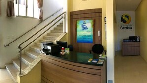 A hotel reception area with a reception desk, a staircase, and a large map on the wall. - Hotel Pousada Santos (Palhoça)