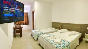 A hotel room with two beds, a TV mounted on the wall, and a small table with a chair. - Hotel Pousada Santos (Palhoça)