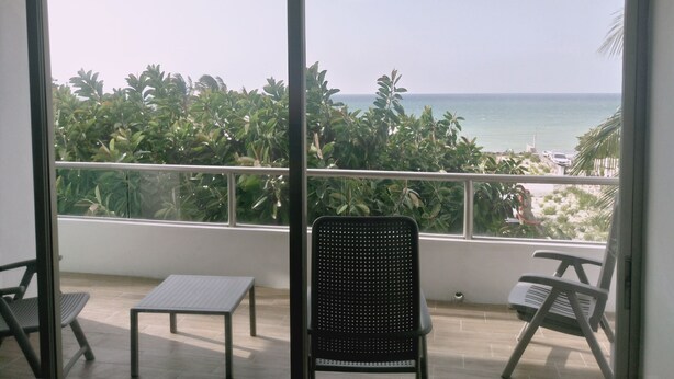 A balcony with a view of the sea, a table, and two chairs. - Osean Oasis Luxury Apartment (Chicxulub Pueblo)