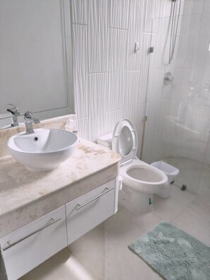A bathroom with a white sink, toilet, and shower. - Osean Oasis Luxury Apartment (Chicxulub Pueblo)