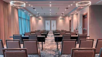 A conference room with rows of chairs, tables, and modern lighting fixtures.