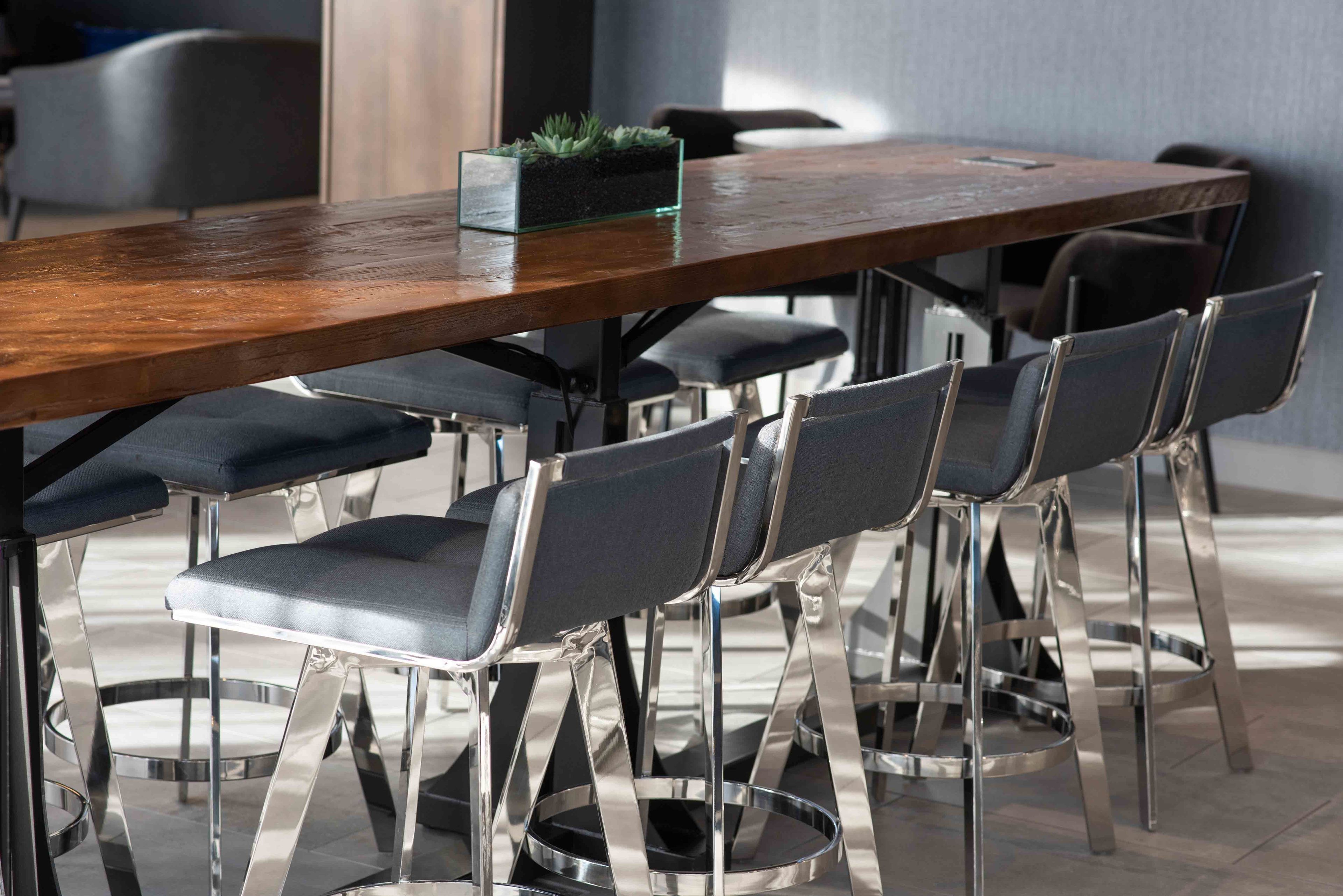 A modern dining area with a wooden table and six metal chairs with cushioned seats.
