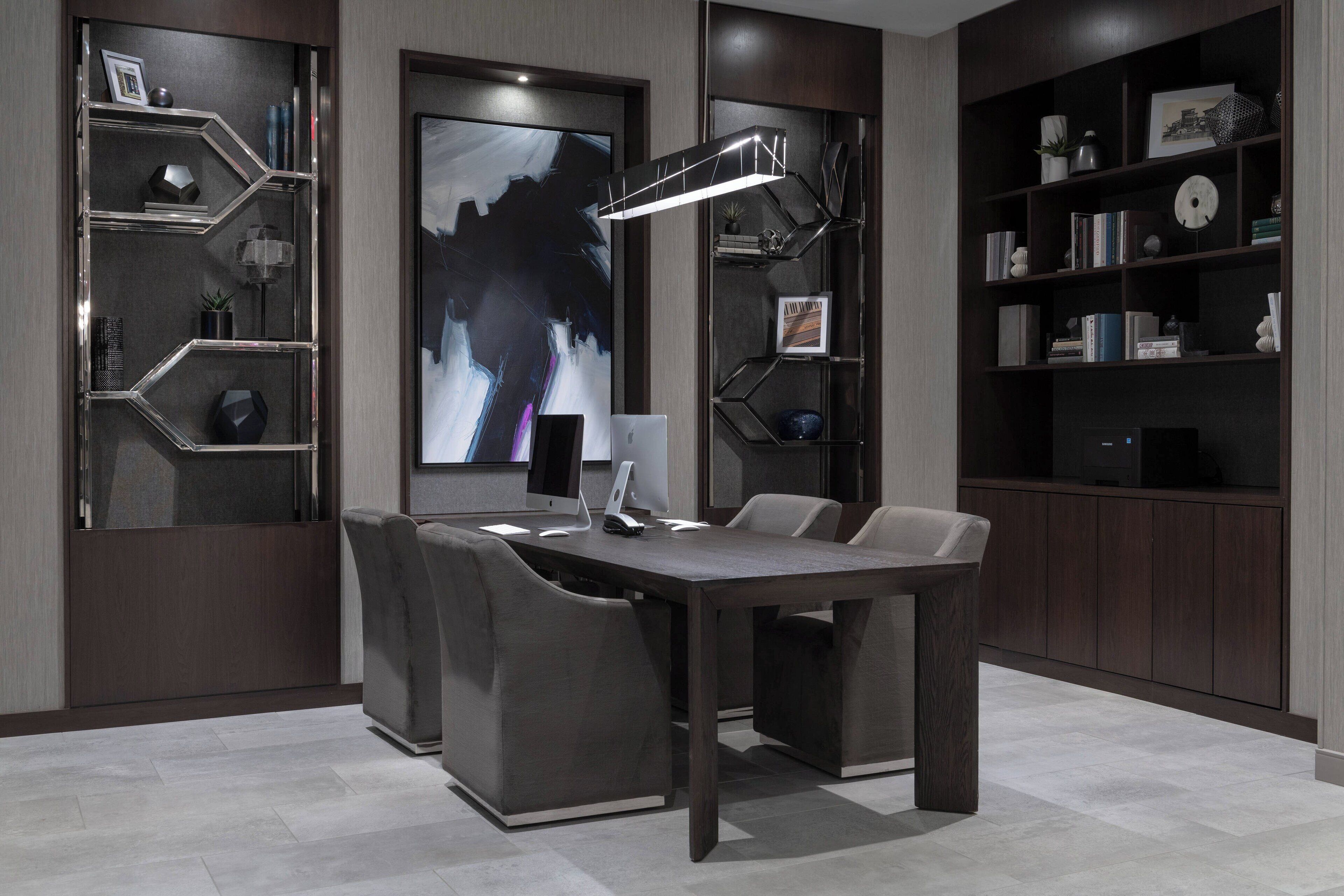 A modern conference room with a dark wooden table, comfortable chairs, and a large abstract painting on the wall.