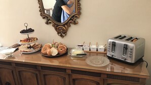 A breakfast buffet with various pastries, a toaster, and a mirror on the wall.