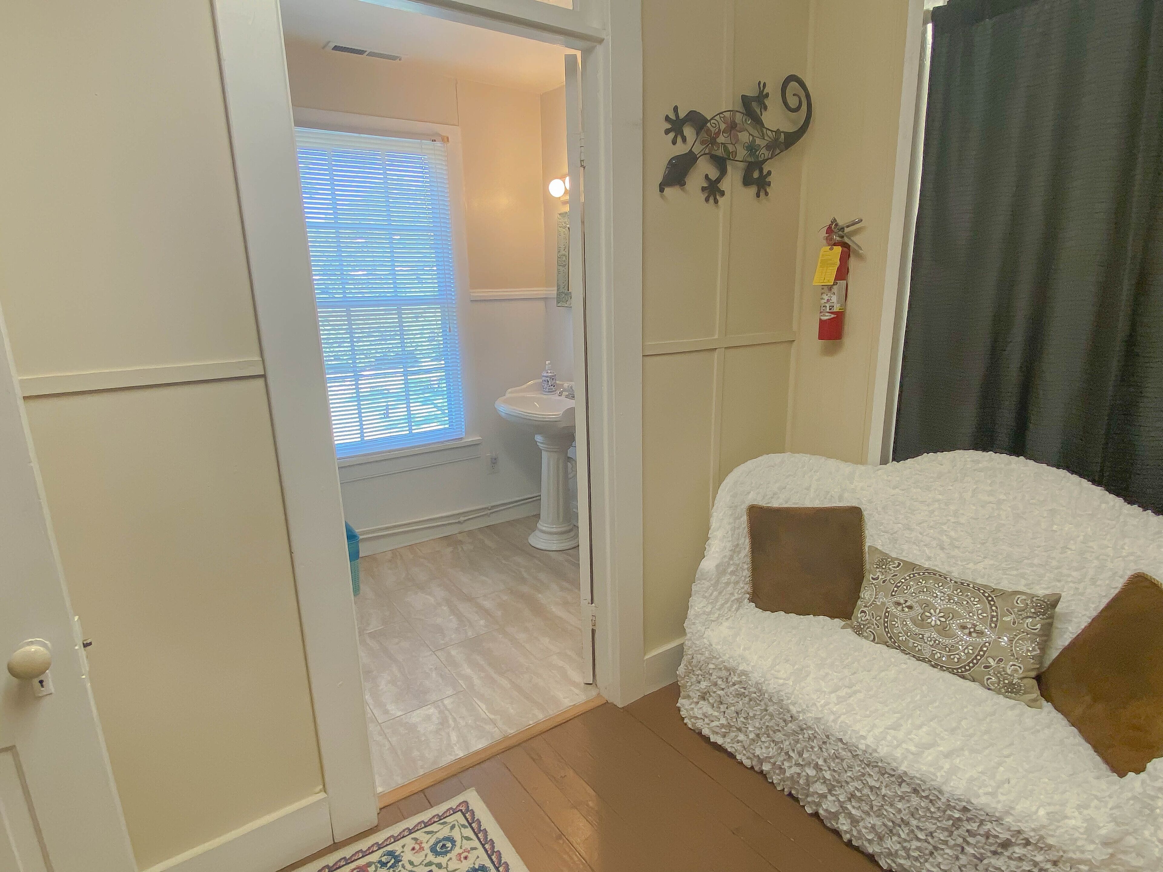 A room with a white sofa, a patterned rug, and a window with blinds.