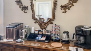 A kitchen counter with a coffee maker, a kettle, a sugar dispenser, and a tea kettle.