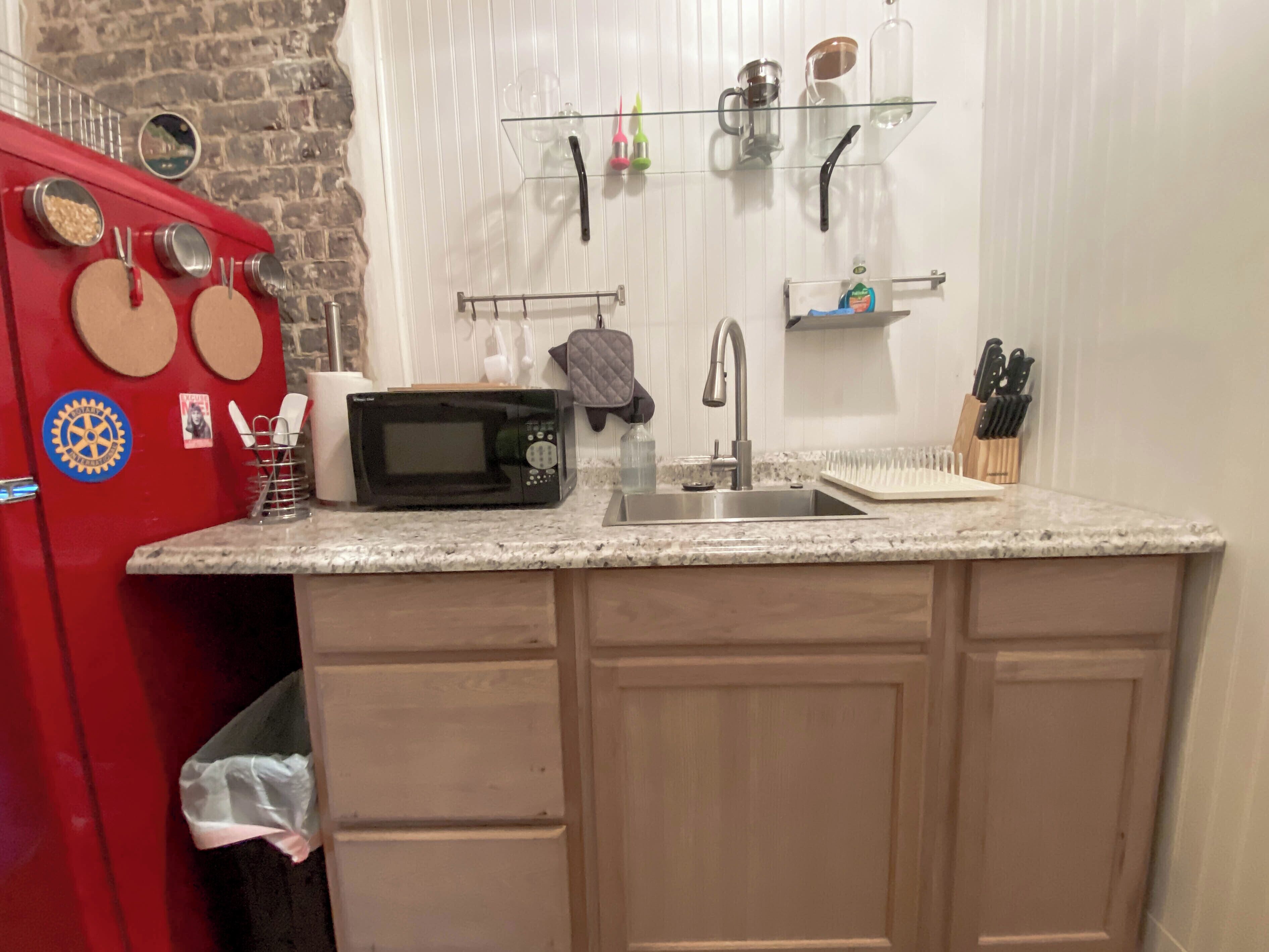A kitchen with a microwave, sink, and red refrigerator.