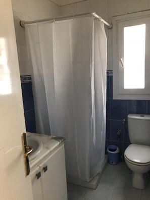 A bathroom with a shower curtain, a toilet, and a sink.