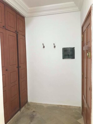A room with a white wall, two small hooks, and a door with a glass panel.