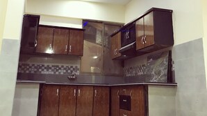 Una cocina con armarios de madera oscura, salpicadero de azulejos e iluminación LED azul en el techo.