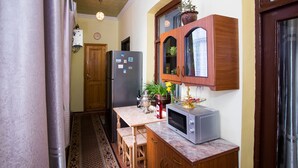 Eine kleine Küche mit Kühlschrank, Mikrowelle, Holzschränken und einer Essecke.
