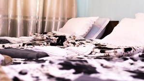 Ein Bett mit einer schwarz-weißen Decke, weißen Kissen und einer weißen Spitzenhäkelarbeit.