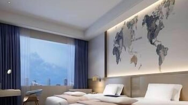A modern hotel room with a large bed, a desk, and a world map on the wall. - Kyriad Hotel (Guangzhou)
