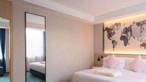 A hotel room with a large bed, a world map on the wall, a mirror, and a blue carpet. - Kyriad Hotel (Guangzhou)