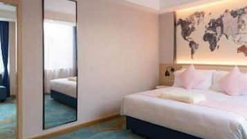 A hotel room with a large bed, a world map on the wall, a mirror, and a blue carpet.