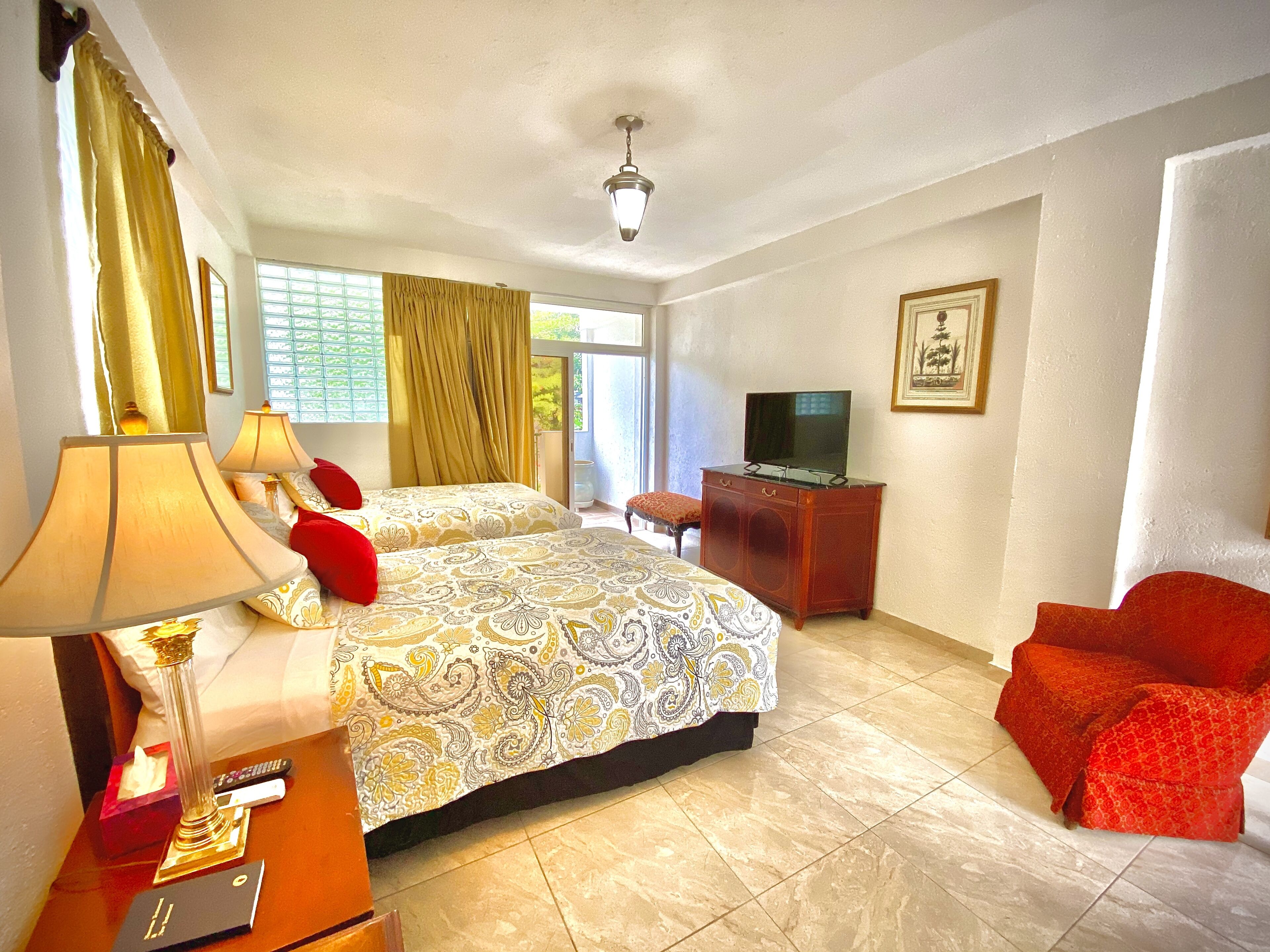 A hotel room with two beds, a TV, a desk, and a chair.