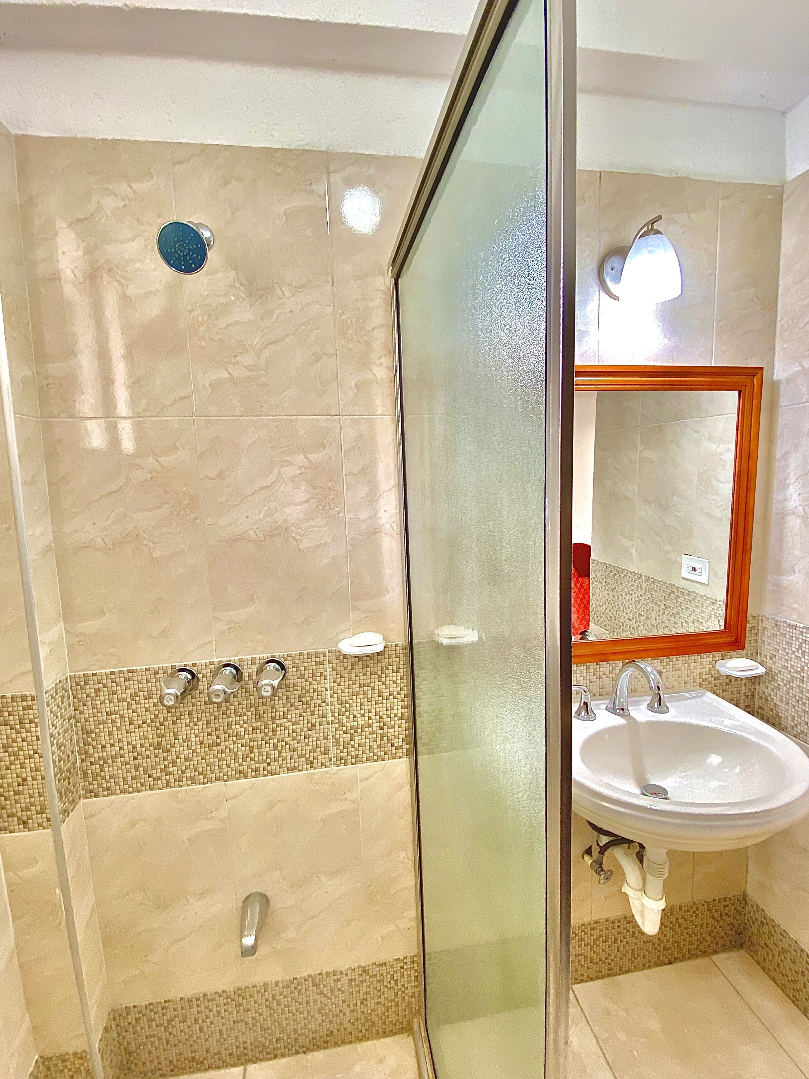 A modern bathroom with a glass-enclosed shower, a sink, and a mirror.