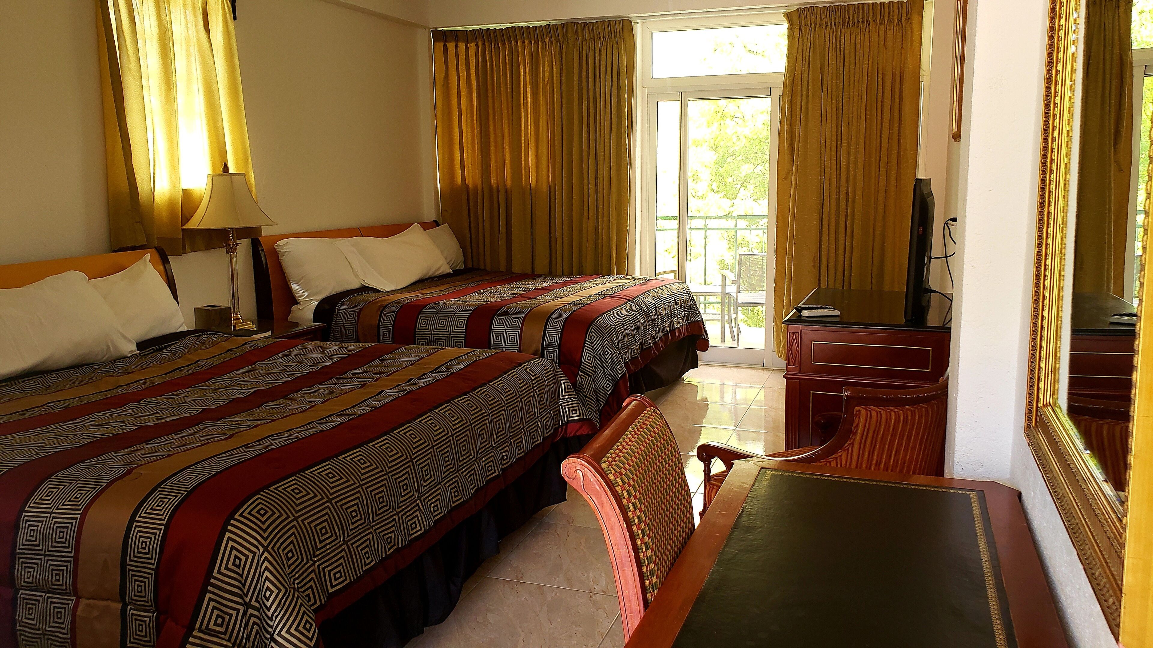 A hotel room with two beds, a desk, and a television.