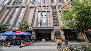 A modern building with a prominent entrance, multiple floors, and a tree in front. - Yi Xiu Boutique Apartment (Guangzhou)