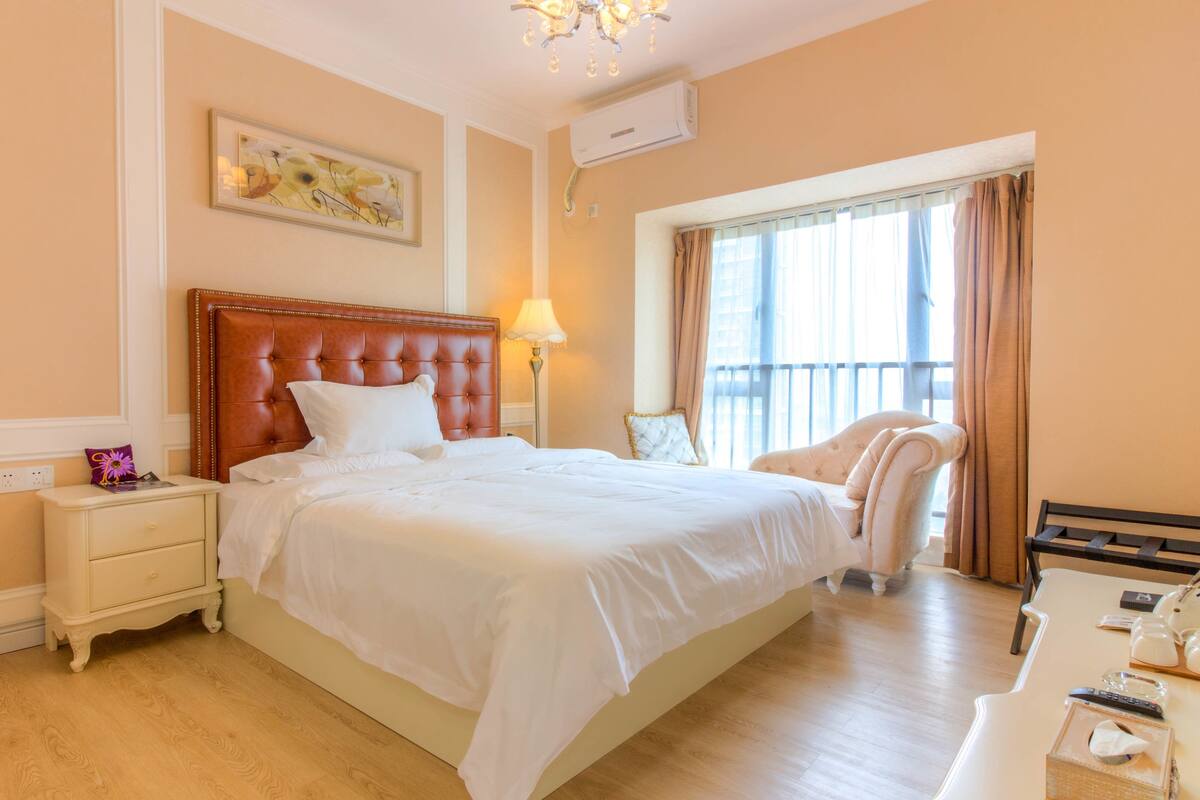 A hotel room with a large bed, a chair, a desk, and a TV.