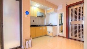 Una cocina con armarios de madera, una campana extractora de acero inoxidable y una puerta doble con celosía metálica.