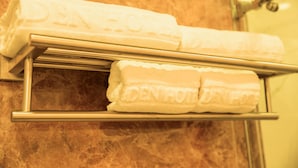 A set of white towels with embossed text on a metal towel rack in a bathroom. - Golden hotel (Hanoi)