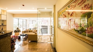 A modern interior with a glass partition, a sofa, a coffee table, and a decorative painting. - Golden hotel (Hanoi)