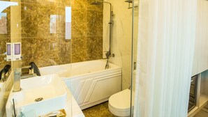 A modern bathroom with a bathtub, toilet, and sink. - Golden hotel (Hanoi)