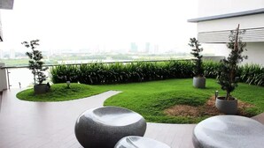 A modern outdoor area with a paved walkway, a grassy section, and potted plants. - Skypod (Puchong)