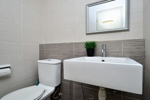 Une salle de bain avec des toilettes, un lavabo et une petite plante en pot.