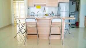 Une cuisine moderne dotée d’un îlot central, de deux tabourets de bar et de meubles de rangement en bois clair.