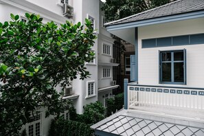 A multi-story building with white exterior walls and blue window frames. - Baan Vajra (Bangkok)