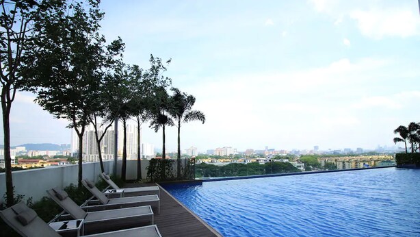Une piscine à débordement avec des chaises longues et une vue sur le paysage urbain.