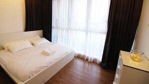 Une chambre d’hôtel avec un grand lit, une commode et une fenêtre avec des rideaux.
