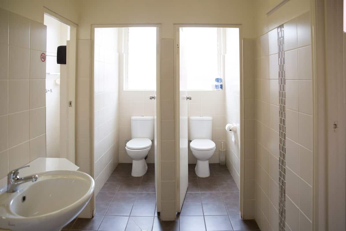 A bathroom with two toilets, a sink, and a shower area.